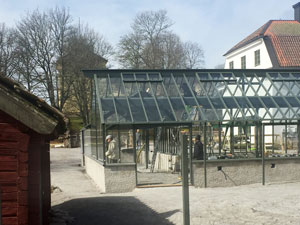 Ett grönmålat växthus under konstrukition på Lövsta slott i Örebrotrakten