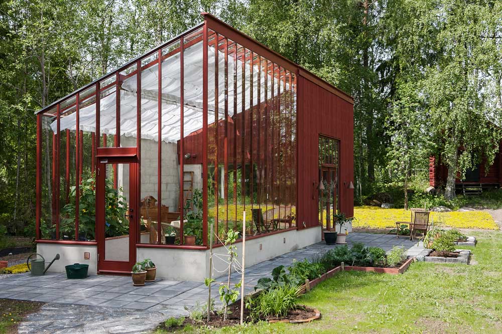 Arkitektritat falurött växthus mot en atelje