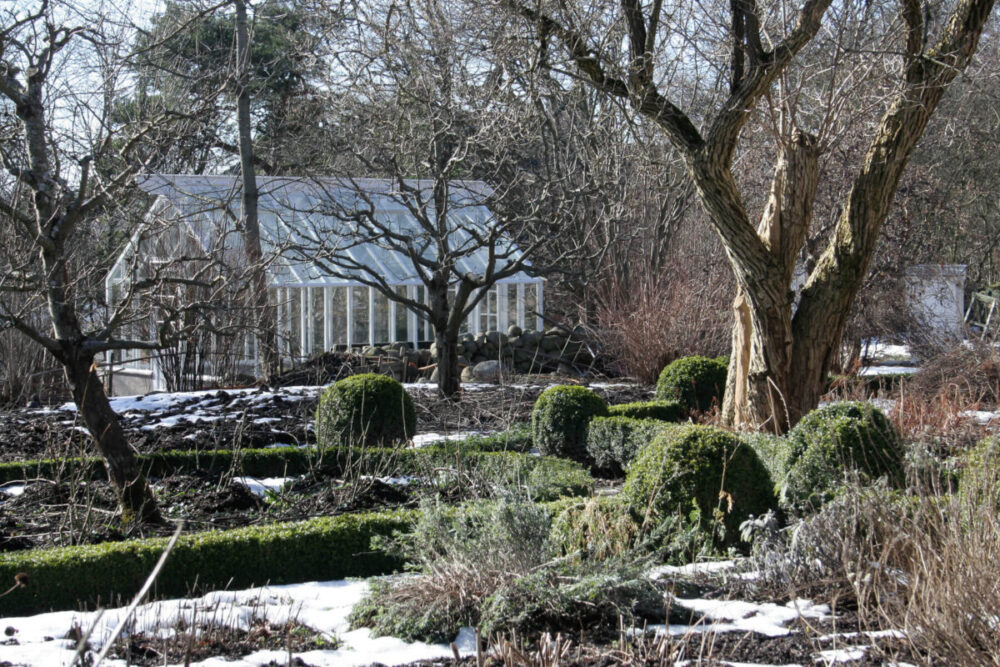 Ett vitt växthus med sadeltak på vintern