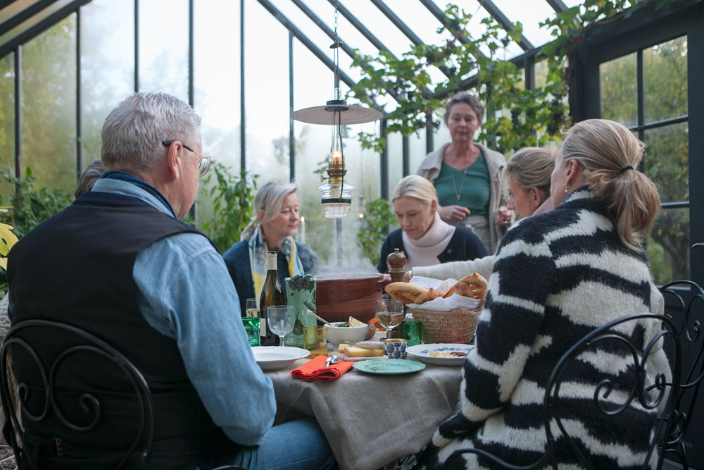 Soppa serveras till sex gäster kring runt bord i växthus.