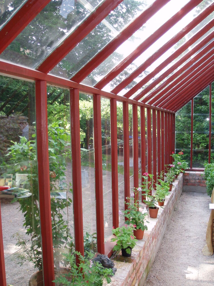 Långsidan på ett tegelstens rött växthus